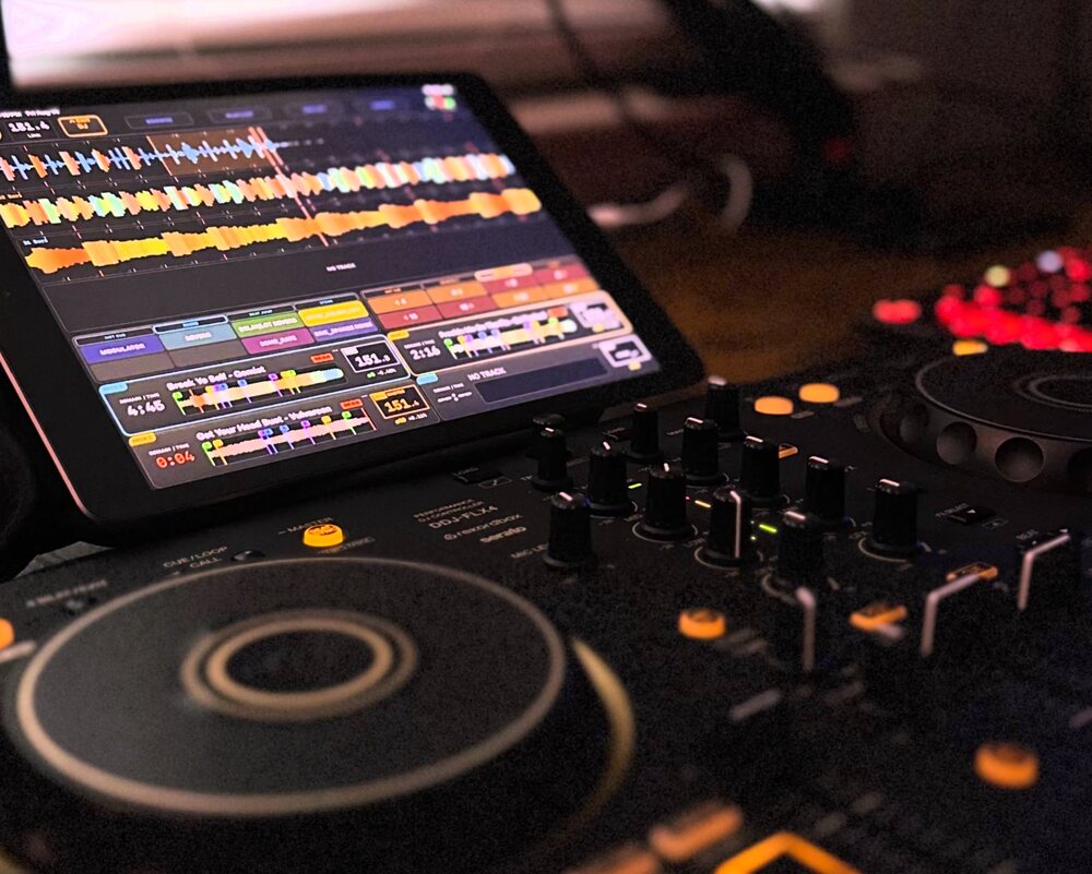 An iPad running MixRack's DJ screen propped above a DDJ-FLX4 controller.